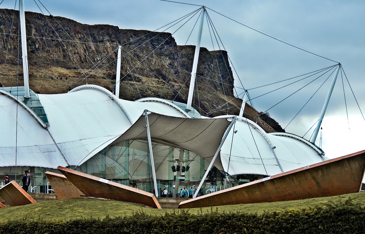 Exterior view of the front facade of Our Dynamic Earth in the foreground with Arthurs Seat in the background, in Edinburgh