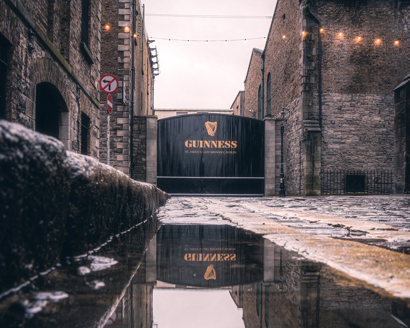 Iconic front gates at the Guinness STorehouse in Dublin, with puddle in foreground showing the gates' reflection